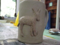 close-up view of unfired clay mug, with relief of zebra on side