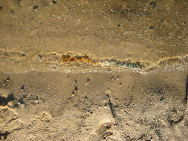photograph of a line of pebbles arranged from orange-brown to white to green-black